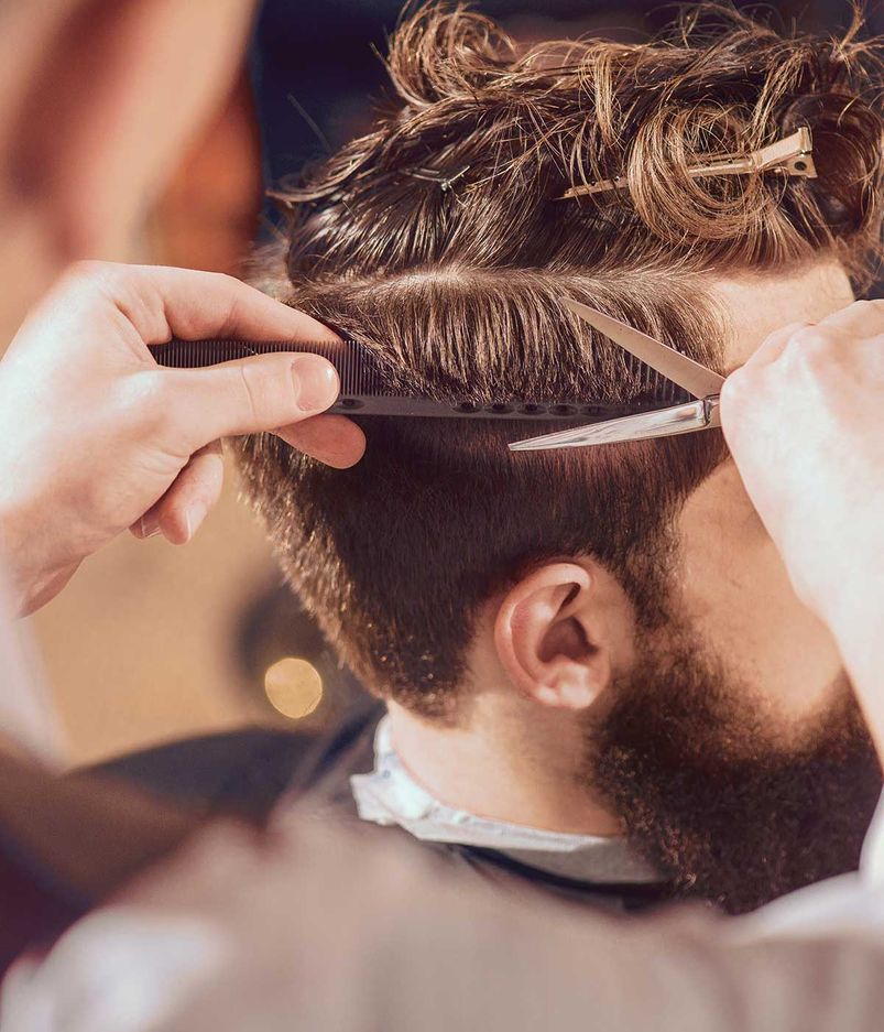 Professioneller Friseur, der die Haare seines Kunden stylt